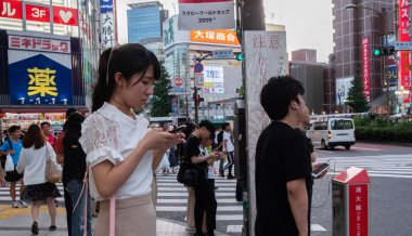 Tokyo, Japonya - 30 Haziran 2018. Kabukicho, Shinjuku içinde karşıdan karşıya bekleyen smartphone ile Japon kız.