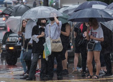 Tokyo, Japonya - 29 Temmuz 2018. Yağmurlu tayfun sezonu boyunca şemsiye ile karşıdan karşıya için bekleyen kişi.