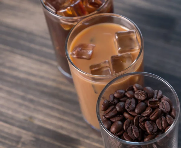 Black iced coffee, cold latte, and beans over wooden background