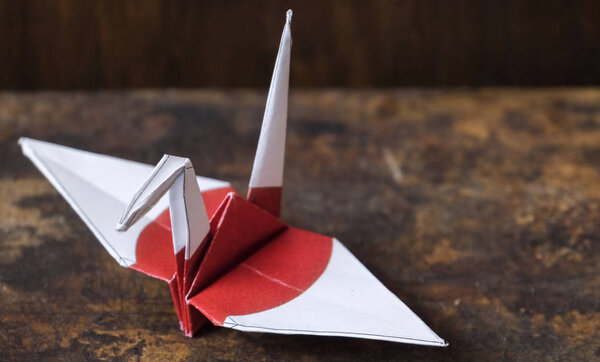 Японский бумажный кран с флагом на деревянном верху стола
