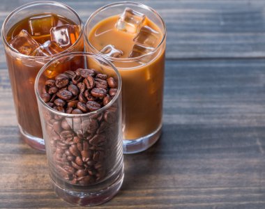 Ahşap arka plan üzerinde siyah kahve, soğuk latte ve fasulye buzlu