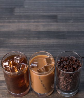 Ahşap arka plan üzerinde siyah kahve, soğuk latte ve fasulye buzlu