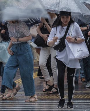 Tokyo, Japonya - 29 Temmuz 2018. Shibuya içinde yağmurlu tayfun sezonunda şemsiye ile Japon kız.