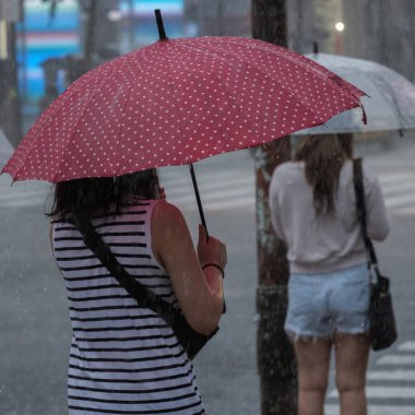 Tokyo, Japonya - 29 Temmuz 2018. Kırmızı şemsiye yağmurlu tayfun sezonu boyunca şemsiye ile karşıdan karşıya bekleyen kadınla.