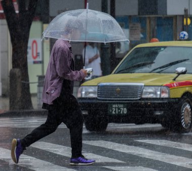 Tokyo, Japonya - 29 Temmuz 2018. Adam yağmurlu tayfun sezonu boyunca Shibuya sokakta şemsiye ile.
