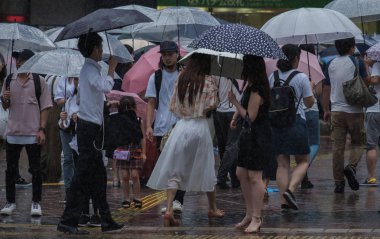 Tokyo, Japonya - 29 Temmuz 2018. Yağmurlu tayfun sezonu boyunca şemsiye ile karşıdan karşıya için bekleyen kişi.