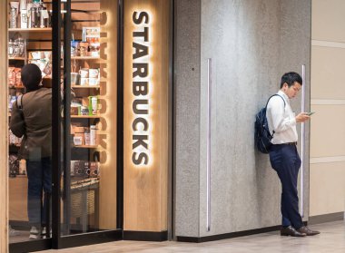 Tokyo, Japonya - 23 Haziran 2018. Starbucks kahvesi Shibuya içinde dışarıda bekleyen smarphone adamla