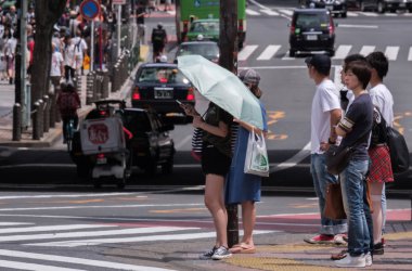 Tokyo, Japonya - 19 Ağustos 2018. Shibuya içinde karşıdan karşıya için bekleyen bir şemsiye tutan smartphone ile Japon kız.