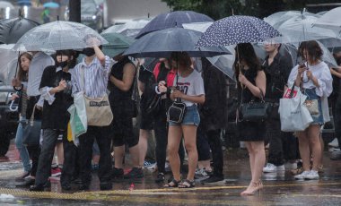 Tokyo, Japonya - 29 Temmuz 2018. Yağmurlu tayfun sezonu boyunca şemsiye ile karşıdan karşıya için bekleyen kişi.