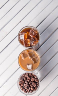 Ahşap arka plan üzerinde siyah kahve, soğuk latte ve fasulye buzlu