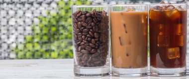 Ahşap arka plan üzerinde siyah kahve, soğuk latte ve fasulye buzlu