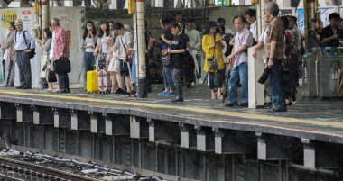 Tokyo, Japonya - 29 Temmuz 2018. Yağmurlu bir günde sırasında Shinjuku Tren İstasyonu platformu tren bekleyen yolcular.