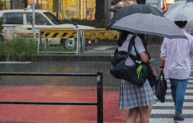 Tokyo, Japonya - 29 Temmuz 2018. Japon liseli kız yağmurlu tayfun sezonu boyunca şemsiye ile karşıya.