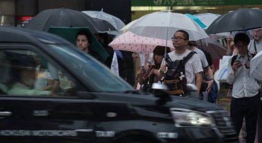 Tokyo, Japonya - 29 Temmuz 2018. Yağmurlu tayfun sezonu boyunca şemsiye ile karşıdan karşıya için bekleyen kişi.