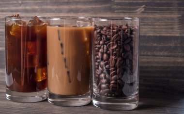 Ahşap arka plan üzerinde siyah kahve, soğuk latte ve fasulye buzlu