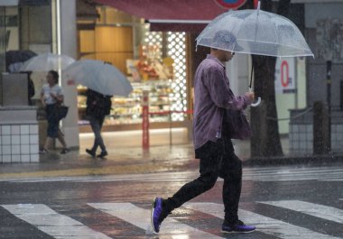 Tokyo, Japonya - 29 Temmuz 2018. Adam yağmurlu tayfun sezonu boyunca Shibuya sokakta şemsiye ile.