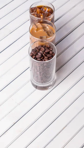 Black iced coffee, cold latte, and beans over wooden background