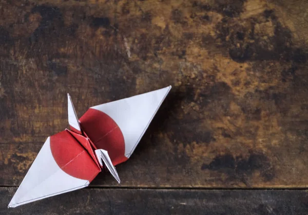 Japanese flag origami paper crane on wooden table top
