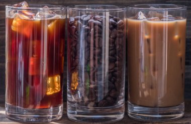 Ahşap arka plan üzerinde siyah kahve, süt kahve ve fasulye buzlu