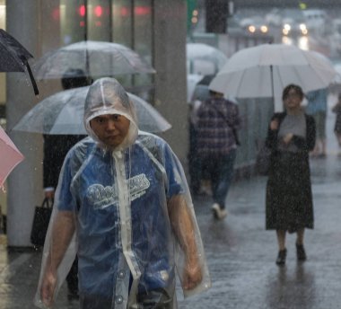 Tokyo, Japonya - 29 Temmuz 2018. Yağmurlu tayfun sezonu boyunca yağmurluk oin Shibuya içinde Japon adam.