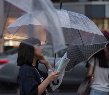 Tokyo, Japonya - 29 Temmuz 2018. Shibuya içinde yağmurlu tayfun sezonunda şemsiye ile Japon kız.
