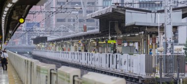 Tokyo, Japonya - 16 Eylül 2018. Bir ışık sabah çiseleyen yağmur sırasında bina Yurakucho istasyonu platformu vie.