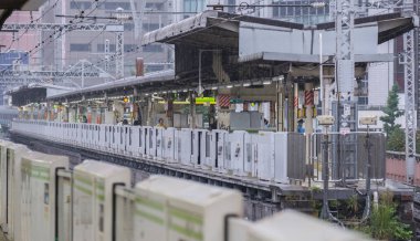 Tokyo, Japonya - 16 Eylül 2018. Bir ışık sabah çiseleyen yağmur sırasında bina Yurakucho istasyonu platformu vie.