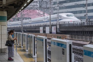 Tokyo, Japonya - 16 Eylül 2018. Arka planda geçirerek bir yüksek spped tren varmak için kadın commuters Yurakucho istasyonu platformu için bekleyen ayakta Tren.