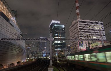 Tokyo, Japonya - 15 Eylül 2018. Blirred hareket thorugh Yurakucho istasyonu geçen Doğu Japonya demiryolu Shonan Shinjuku satırının geceleri izler... Uzun pozlama süresi.