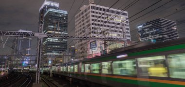 Tokyo, Japonya - 15 Eylül 2018. Blirred hareket thorugh Yurakucho istasyonu geçen Doğu Japonya demiryolu Shonan Shinjuku satırının geceleri izler... Uzun pozlama süresi.