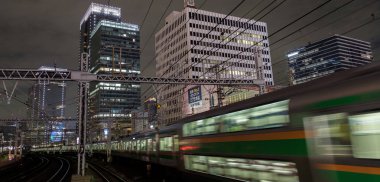 Tokyo, Japonya - 15 Eylül 2018. Blirred hareket thorugh Yurakucho istasyonu geçen Doğu Japonya demiryolu Shonan Shinjuku satırının geceleri izler... Uzun pozlama süresi.