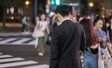 Tokyo, Japonya - 15 Eylül 2018. Geceleri Yurakucho sokakta geçmeye bekleyen iş takım elbiseli adam.