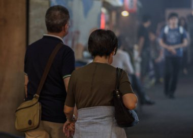 Tokyo, Japonya - 15 Eylül 2018. Yaşlı Jpanese çift raylı altında bir tünel geçişi dumanlı küçük atılmış yürüyüş Yurakucho sokakta geceleri izlemek..