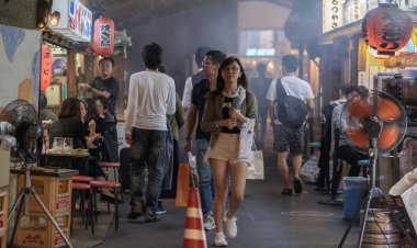 TOKYO, JAPAN - SEPTEMBER 15TH, 2018. Pedestrian walking pass smoky small eateries in a tunnel under rail track in Yurakucho alley at night. clipart