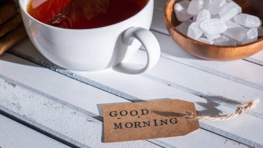 Beyaz ahşap arka planda çay fincan ile Günaydın etiket görünümü yakın