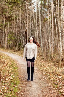 Portrt einer jungen Frau mit langen Haaren stehend im herbstlichen Wald 
