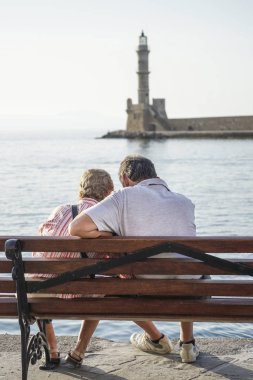 Bir çift deniz karşı bankta oturmuş ve şaşırtıcı deniz feneri izlemek