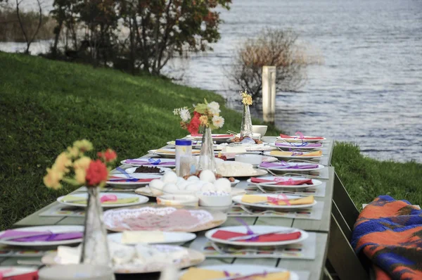 A fancy picnic table full of food by lake in summer