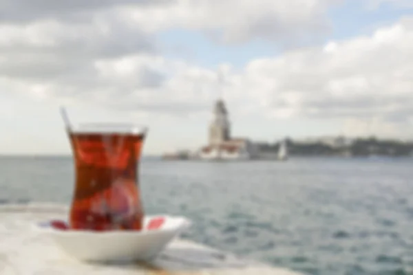 Verschwommener Hintergrund mit einem Glas türkischen Tee gegen das Meer — Stockfoto