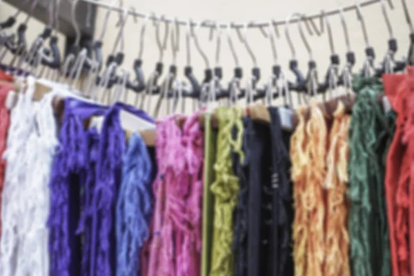 blurred background with some hanged colorful clothes in a shop