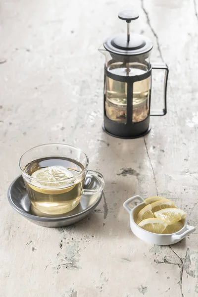 Стакан травяного чая и чайник на деревянном столе — стоковое фото