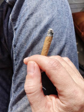 el parmaklarının arasında bir sigara tutarak 