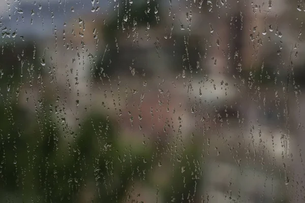 Lluvia de fondo cae sobre un cristal de ventana — Foto de Stock