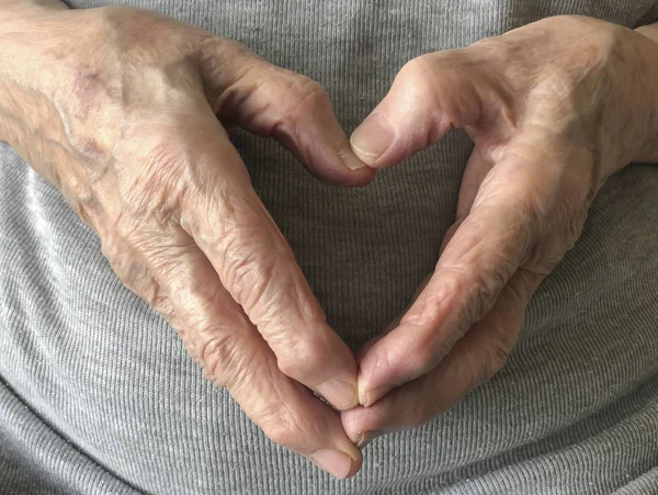wrinkled hands of a senior person, making heart shape