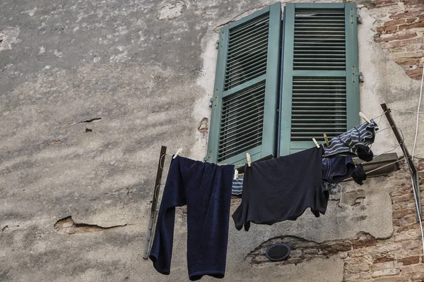 Ropa colgada por una ventana verde ciega de un edificio — Foto de Stock