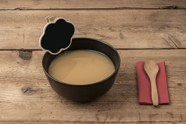 Суп и пустая доска на деревянном столе — стоковое фото