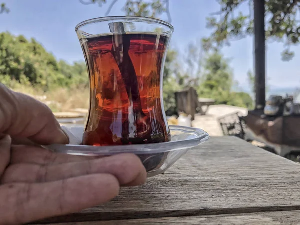 Hand hält ein Glas türkischen Tee auf einem Holztisch — Stockfoto