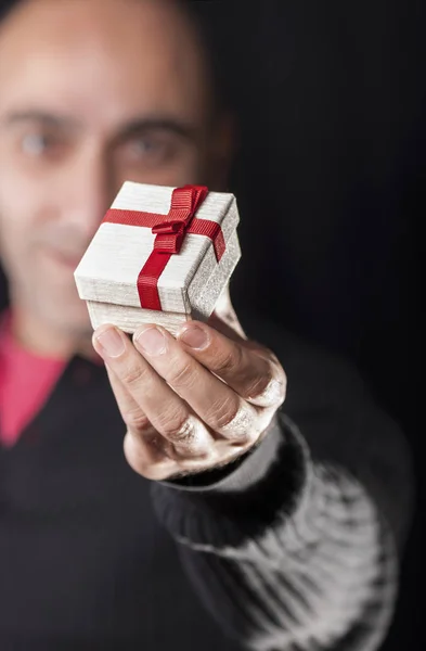 A man holding a gift box in order to give