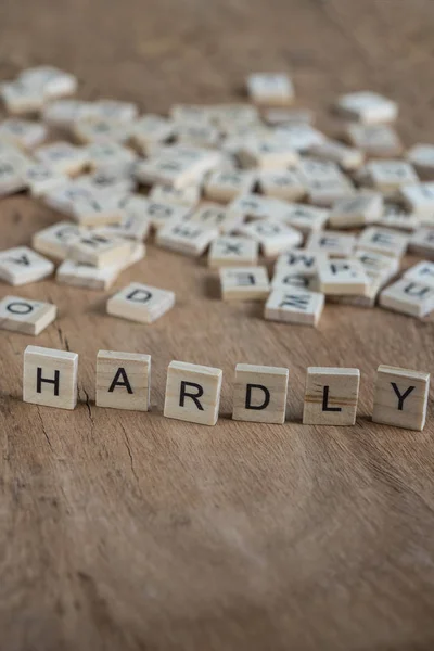 The word hardly written with cube letters on wood background — Stock Photo, Image
