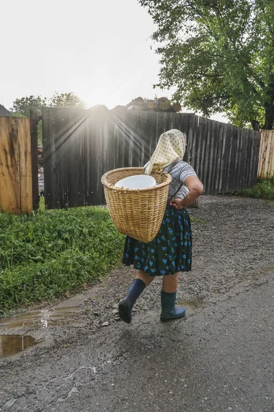 Köyde sırtında sepet taşıyan bir kadın.